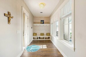 Ein Korridor mit einer Holzbank, einem Kruzifix und einer Chandelier.