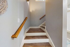 Eine Treppe mit Holzwegen und einem Geländer, die zu einer Zwischenebene mit einem Lichtschalter führt.