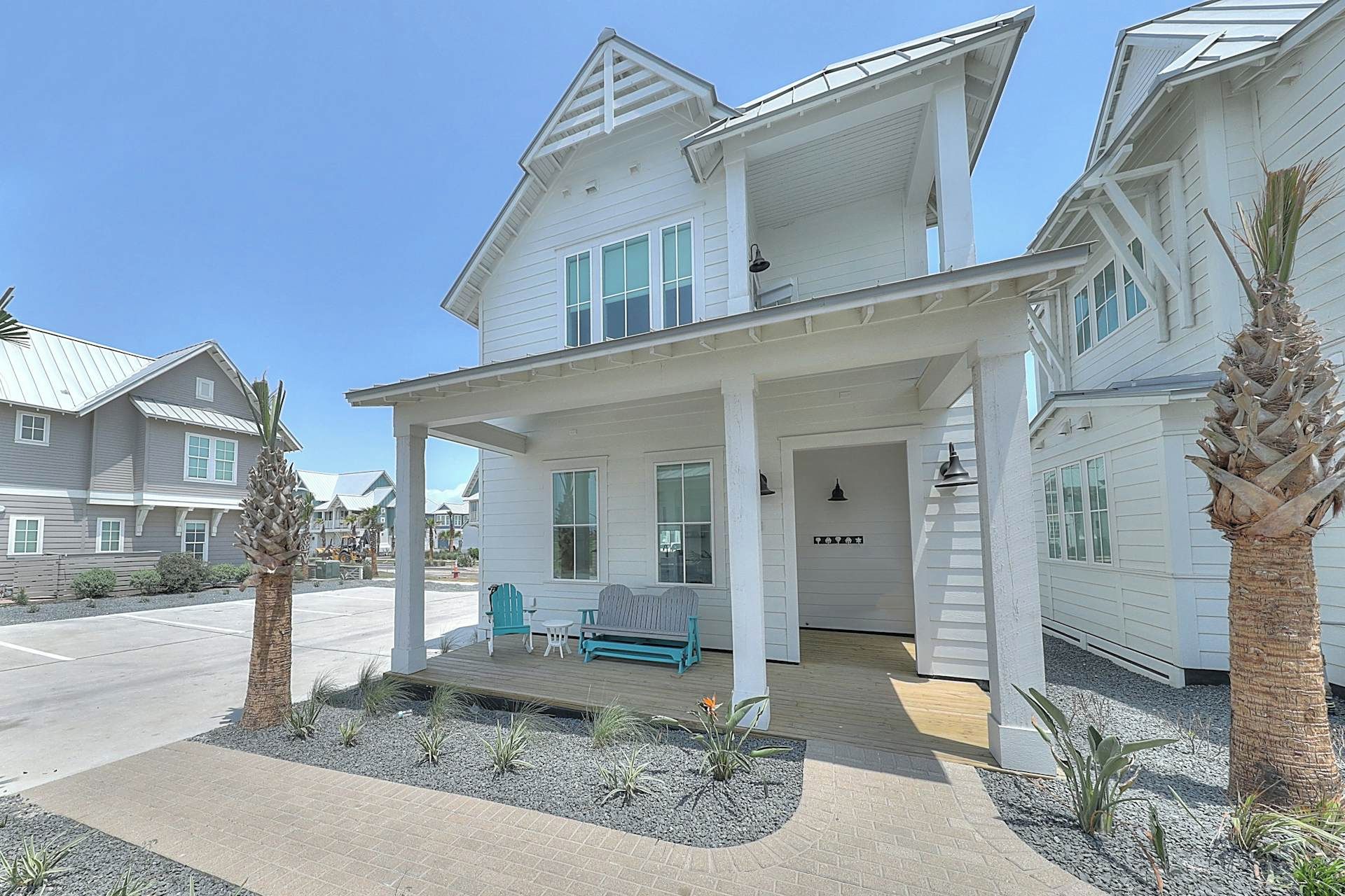 A two-story house with a porch, a small garden, and a clear sky.