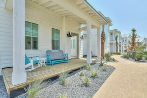 A covered porch with a wooden deck, a bench, and a table. - At Ease | Golf Views | Steps to Beach (Port Aransas)