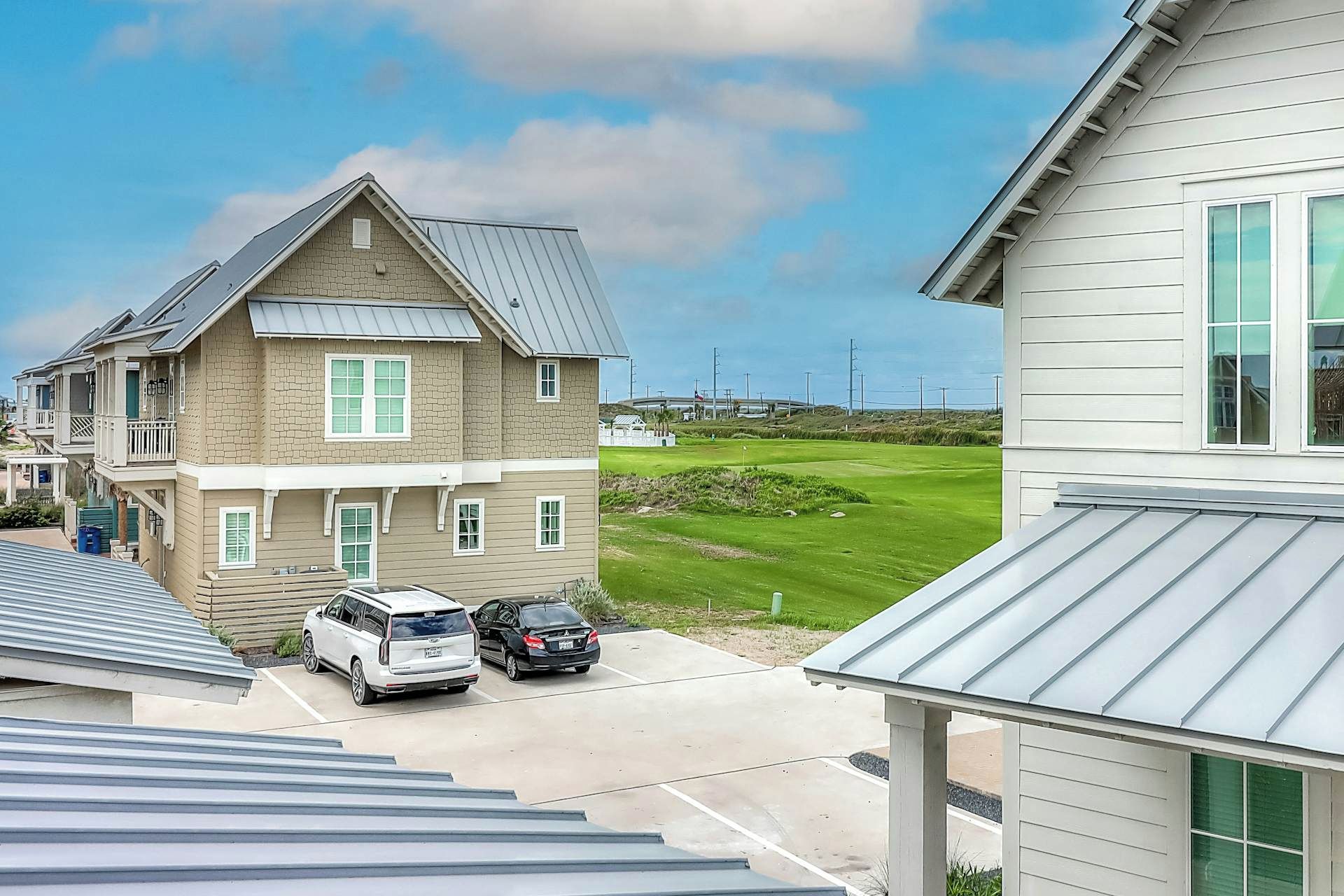 Ett bostadsområde med hus, en golfbana och parkerade bilar.
