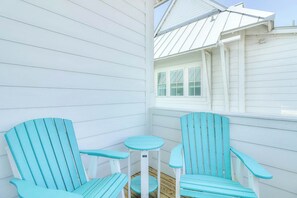 A corner of a room with two turquoise Adirondack chairs and a small round table. - Beach Days and Fairways | Golf Views (Port Aransas)