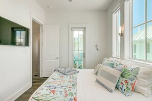 Ein Schlafzimmer mit einem Bett, einem Fenster und einer Tür, die auf einen Balkon führt.