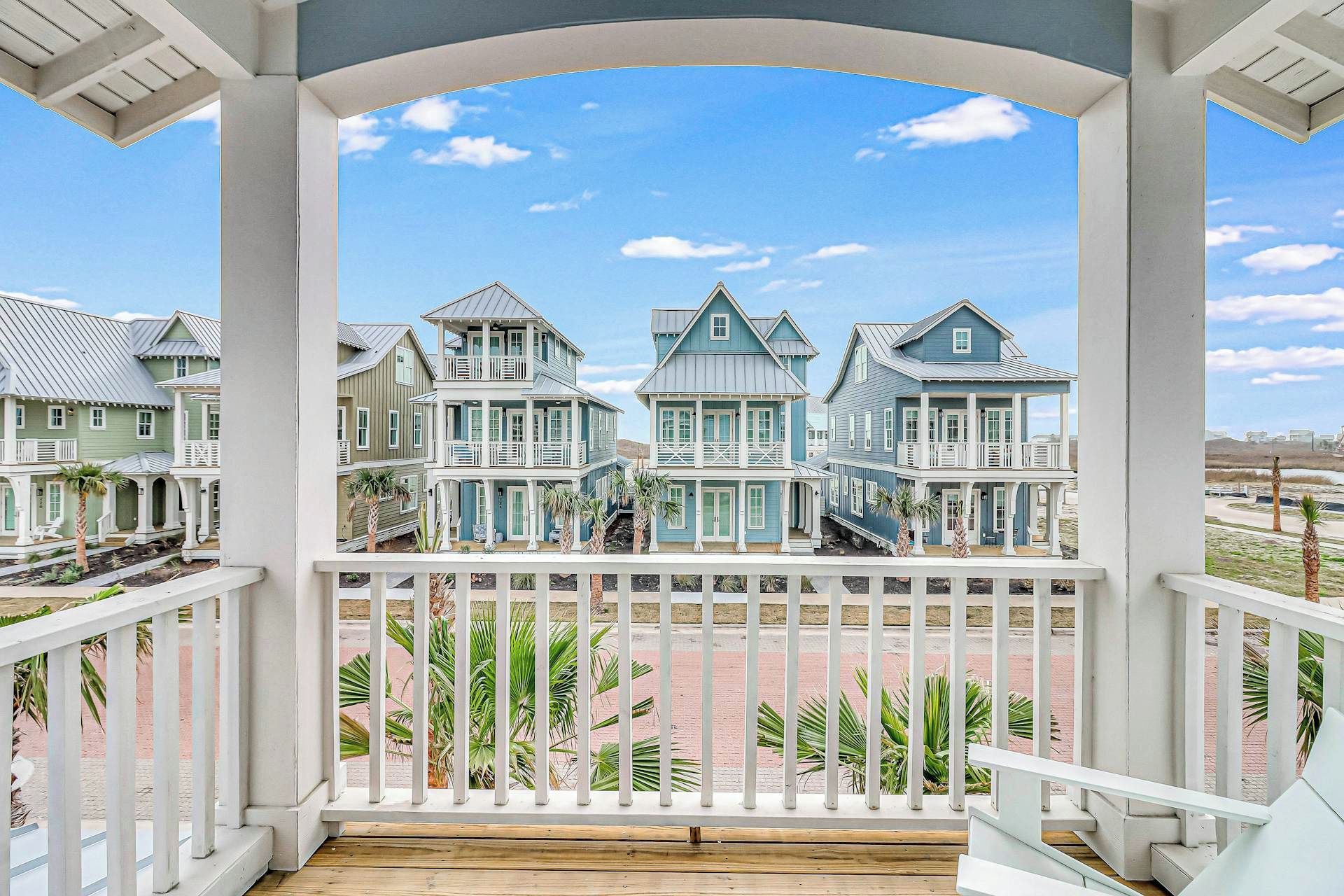 A covered porch with a view of a row of houses.