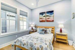 A bedroom with a bed, two nightstands, a window with blinds, and two wall-mounted paintings. - Allen's Anchor | Pet Friendly | Steps to Beach (Port Aransas)