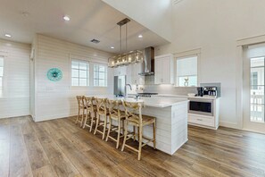 A spacious kitchen with a central island, wooden chairs, and modern appliances. - The Sandcastle | Gulf Views | Private Elevatorv (Port Aransas)