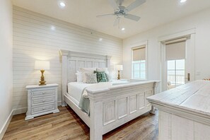 Quarto com cama, mesas de cabeceira, penteadeira e ventilador de teto.