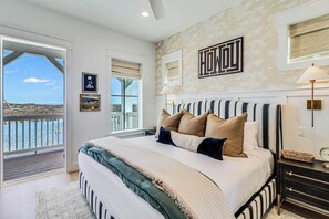Ein Schlafzimmer mit einem großen Bett, Blick ins Freie und einem Wandbild.