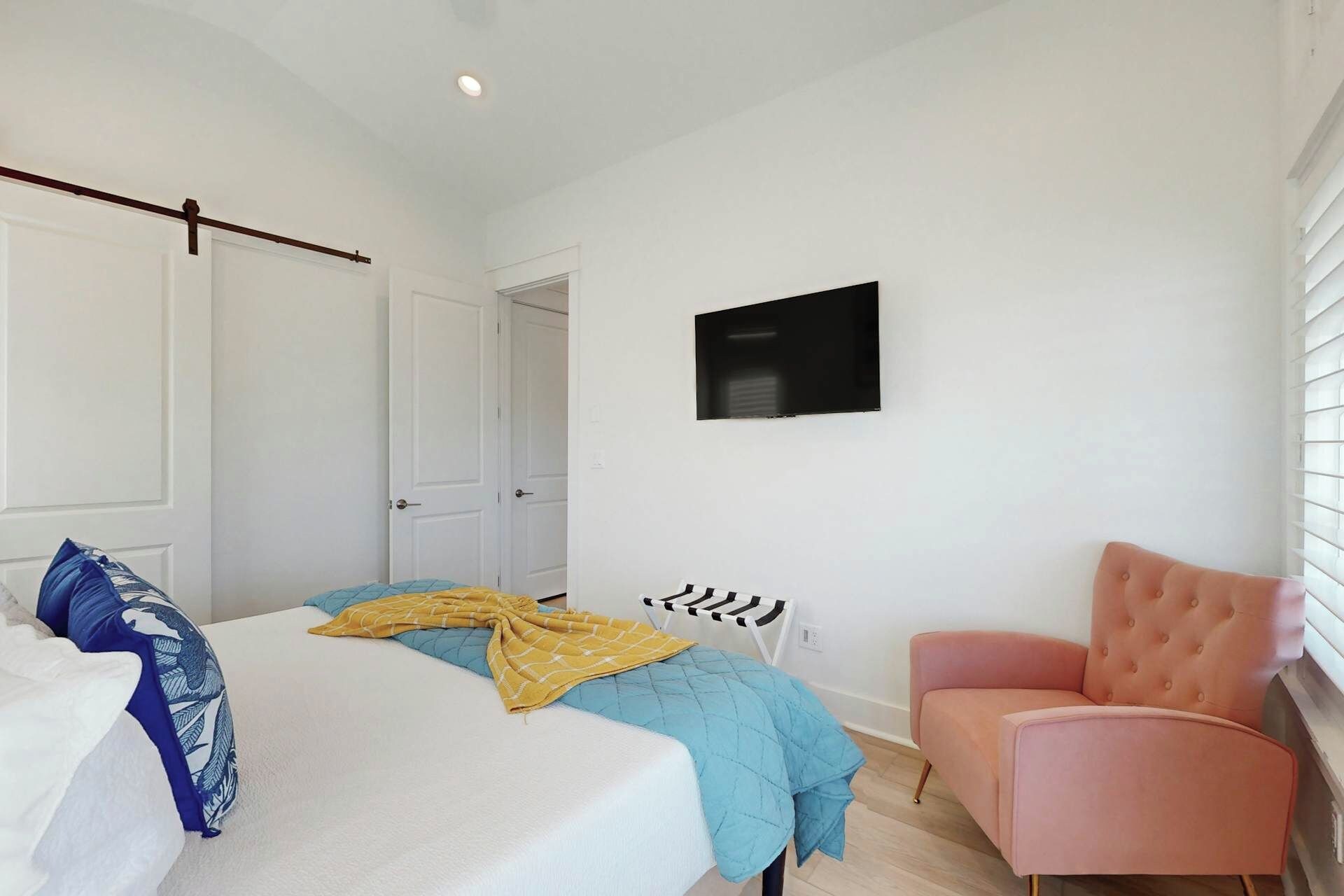 Une chambre à coucher avec un lit, une chaise, une télévision et une porte.