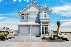 A two-story house with a gabled roof, two garage doors, and a small porch. - Casa Vela at Palmilla | Steps to Beach and Resort (Port Aransas)
