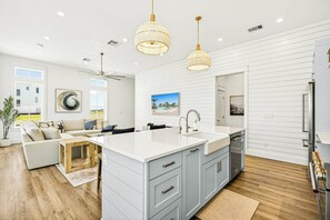 A modern kitchen with a large island, white cabinetry, and pendant lighting. - Casa Vela at Palmilla | Steps to Beach and Resort (Port Aransas)
