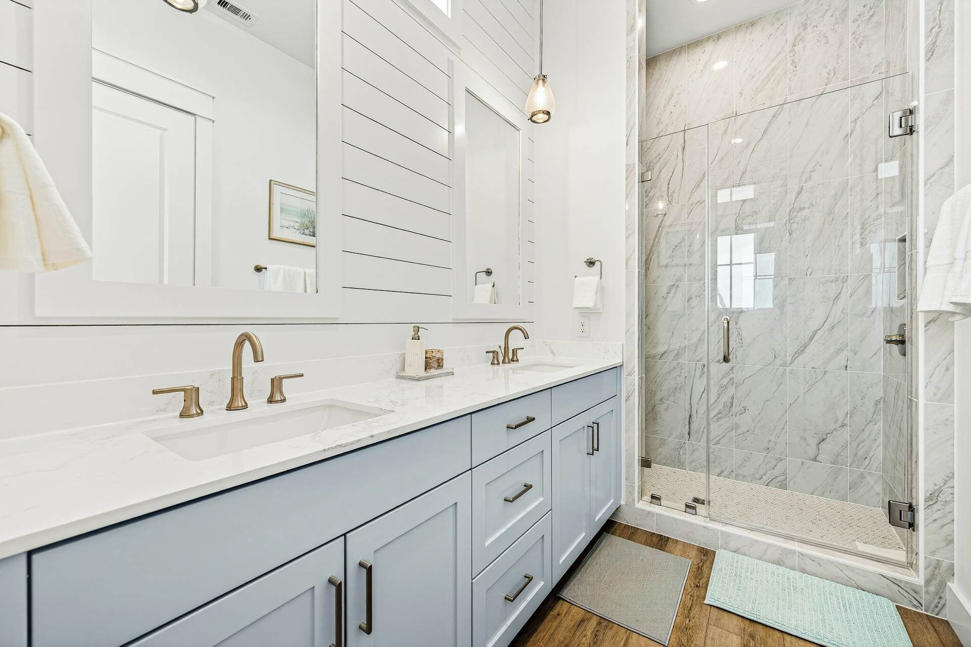 A modern bathroom with a large mirror, two sinks, and a shower area.