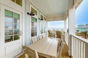En inglasad veranda med ett bord och stolar, stora fönster och utsikt över andra byggnader.