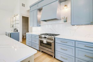 Eine moderne Küche mit einer zentralen Kochinsel, einem eingebauten Backofen und hellblauen Schränken.