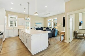 A modern kitchen with white cabinetry, a central island, pendant lighting, and a ceiling fan. - Ocean Pearl | Pet Friendly | Steps to Beach (Port Aransas)