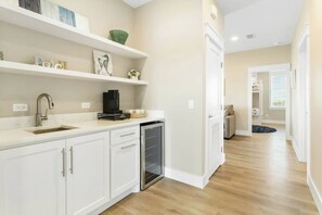 A modern kitchen with white cabinetry, a built-in dishwasher, and a coffee maker on the counter. - Ocean Pearl | Pet Friendly | Steps to Beach (Port Aransas)