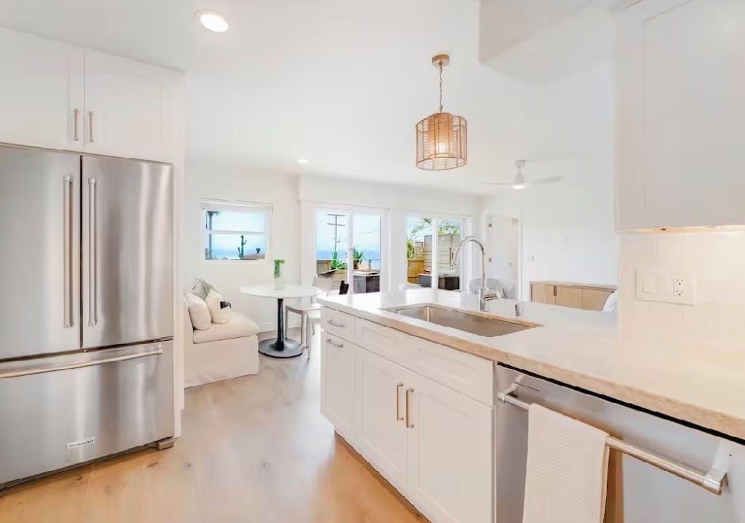 A modern kitchen with stainless steel appliances, a central island, and a pendant light.