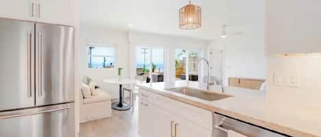 A modern kitchen with stainless steel appliances, a central island, and a pendant light.