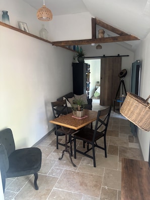 A dining area with a wooden table and chairs, a potted plant, and a hanging light fixture. - The Ty'lochois (Loches)