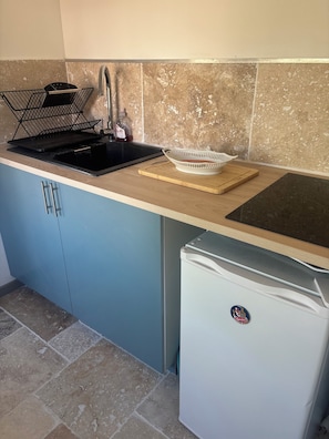 A kitchen with a sink, a dish rack, a cutting board, and a refrigerator. - Vrbo Property (Loches)