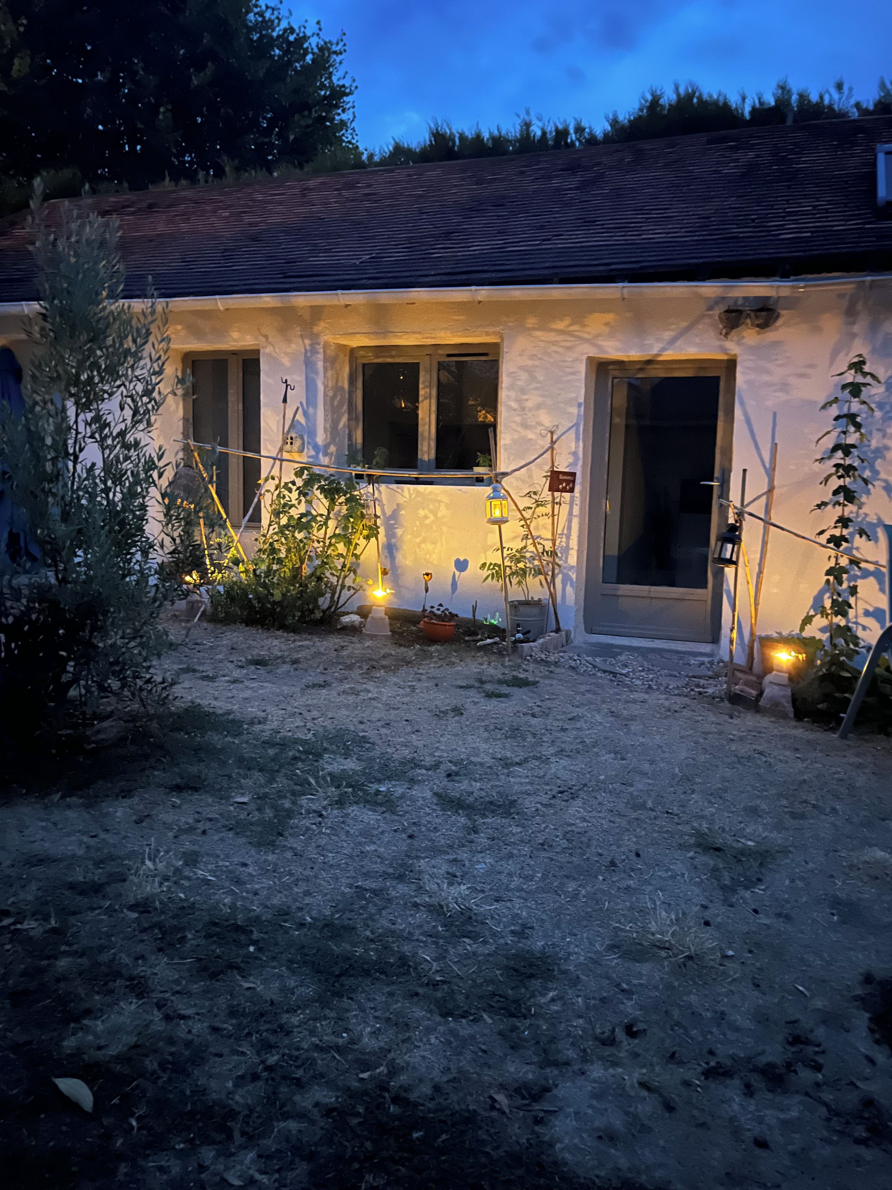 A house with a gravel driveway, a wooden door, and a window with a light fixture.