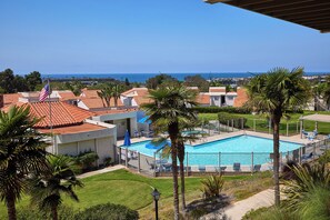 A hotel with a swimming pool, palm trees, and a view of the ocean. - Beautiful 2-bedroom condo in Carlsbad near the beach, with pool, and ocean view! (Carlsbad)