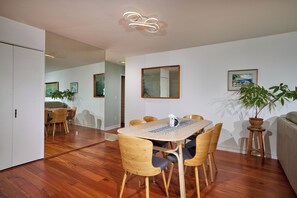A dining area with a wooden table and chairs, a mirror on the wall, and potted plants. - Beautiful 2-bedroom condo in Carlsbad near the beach, with pool, and ocean view! (Carlsbad)