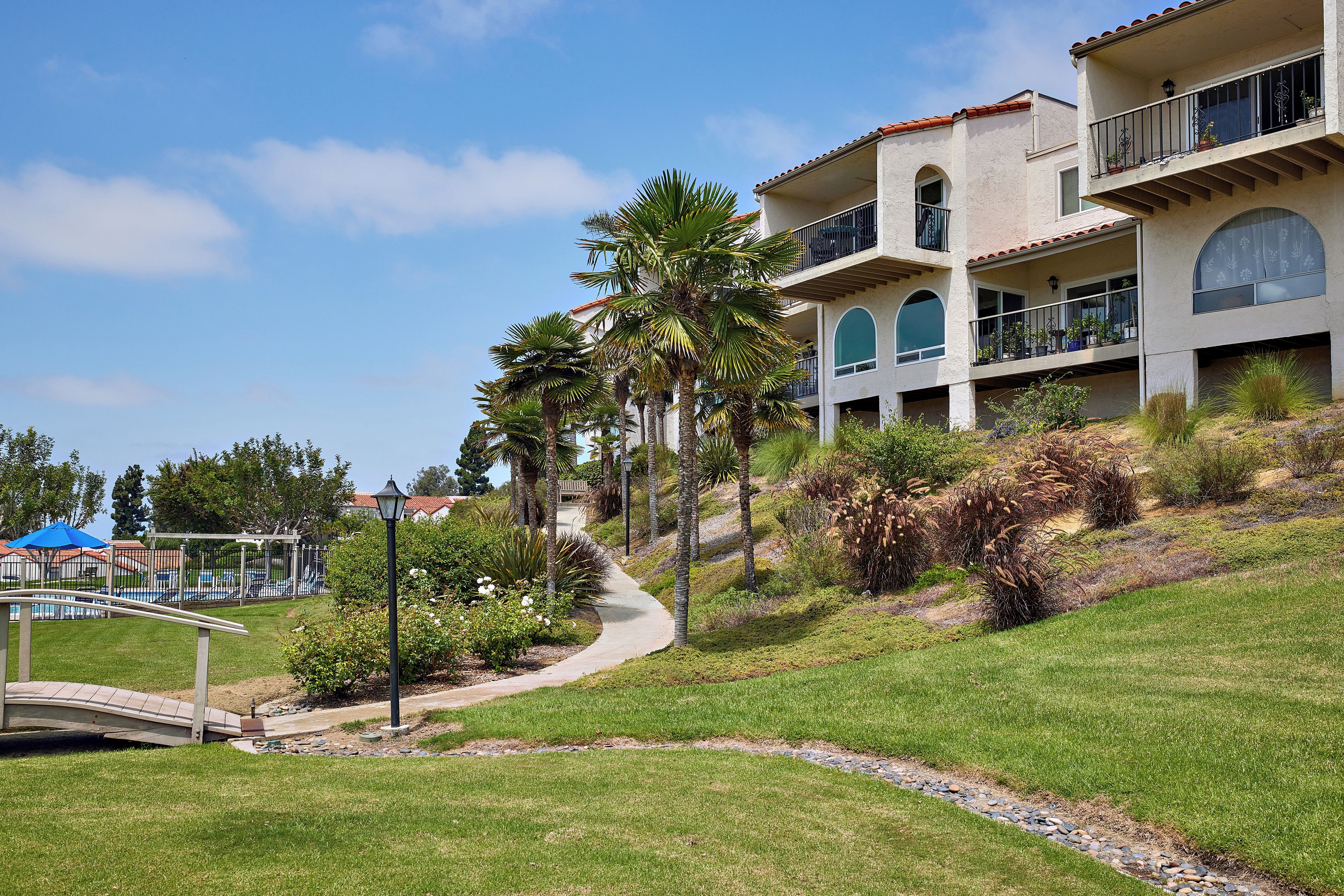 A multi-story building with balconies, a pathway, and a pool area.