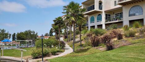 A multi-story building with balconies, a pathway, and a pool area.