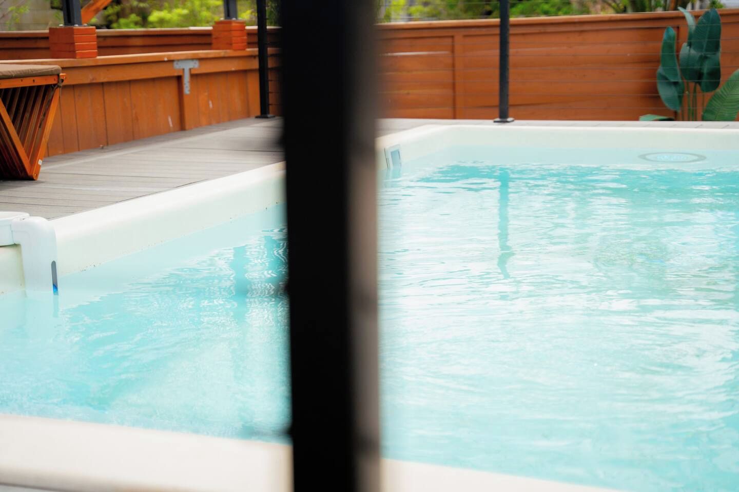 Une piscine avec une terrasse en bois et un jacuzzi.