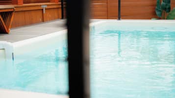 Une piscine avec une terrasse en bois et un jacuzzi.