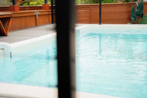 A swimming pool with a wooden deck and a hot tub.