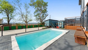 En swimmingpool med en træterrasse, en mindre bygning og havudsigt.