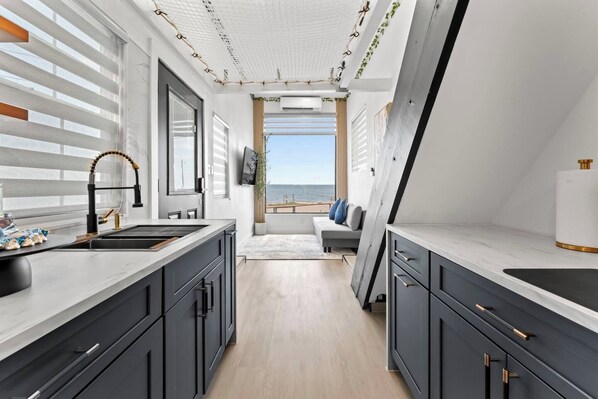 A modern kitchen with a large window, a built-in oven, and a view of the sea.