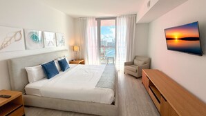 Habitación de hotel con una cama grande, un escritorio, una silla y vistas de la ciudad por la ventana.