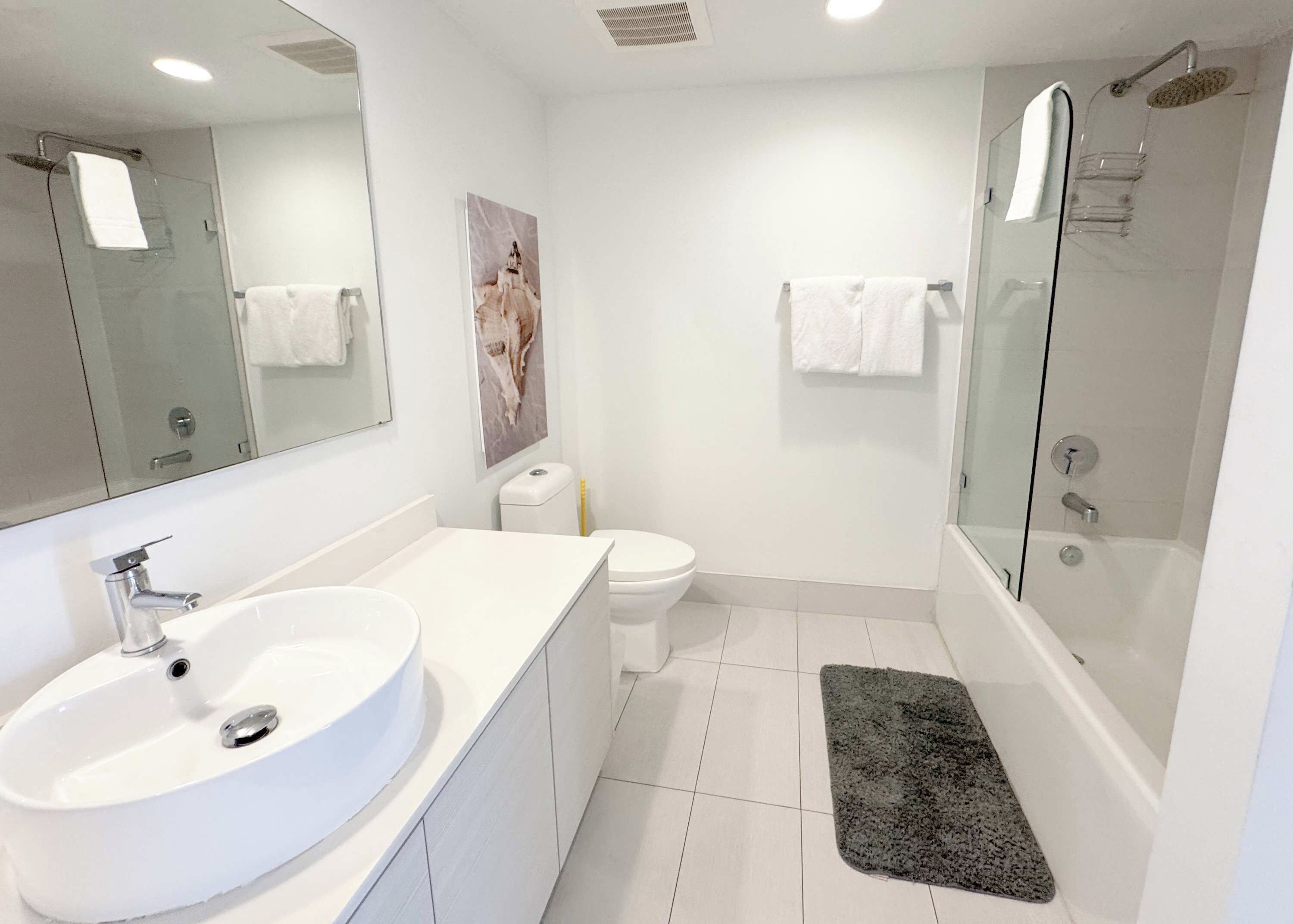 A modern bathroom with a large sink, toilet, and shower.