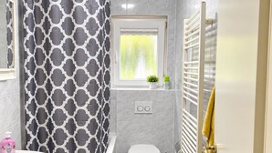 A modern bathroom with a bathtub, toilet, sink, and a window. - Spacious apartment with a parking space and a sunroom. (Iserlohn)