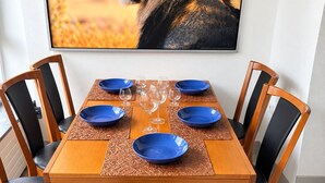 A dining table set with blue plates and wine glasses, surrounded by chairs with black cushions. - Spacious apartment with a parking space and a sunroom. (Iserlohn)