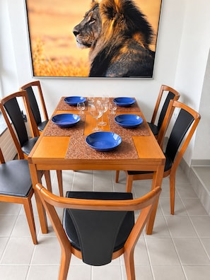 Spisebord dækket med blå tallerkener og vinglas, omgivet af stole med sorte hynder.
