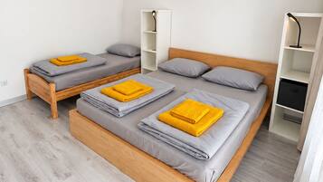 Ein Schlafzimmer mit zwei Betten, einem Holzkopfstück, einem weißen Wäscheschrank und einer kleinen Regaleinrichtung.