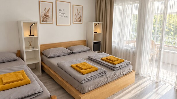 A hotel room with two beds, a wooden headboard, a bedside table, a lamp, and a window with curtains. - Spacious apartment with a parking space and a sunroom. (Iserlohn)