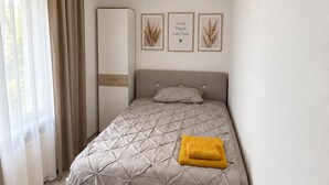A bedroom with a bed, a bedside table, a wardrobe, and a wall with framed pictures. - Spacious apartment with a parking space and a sunroom. (Iserlohn)