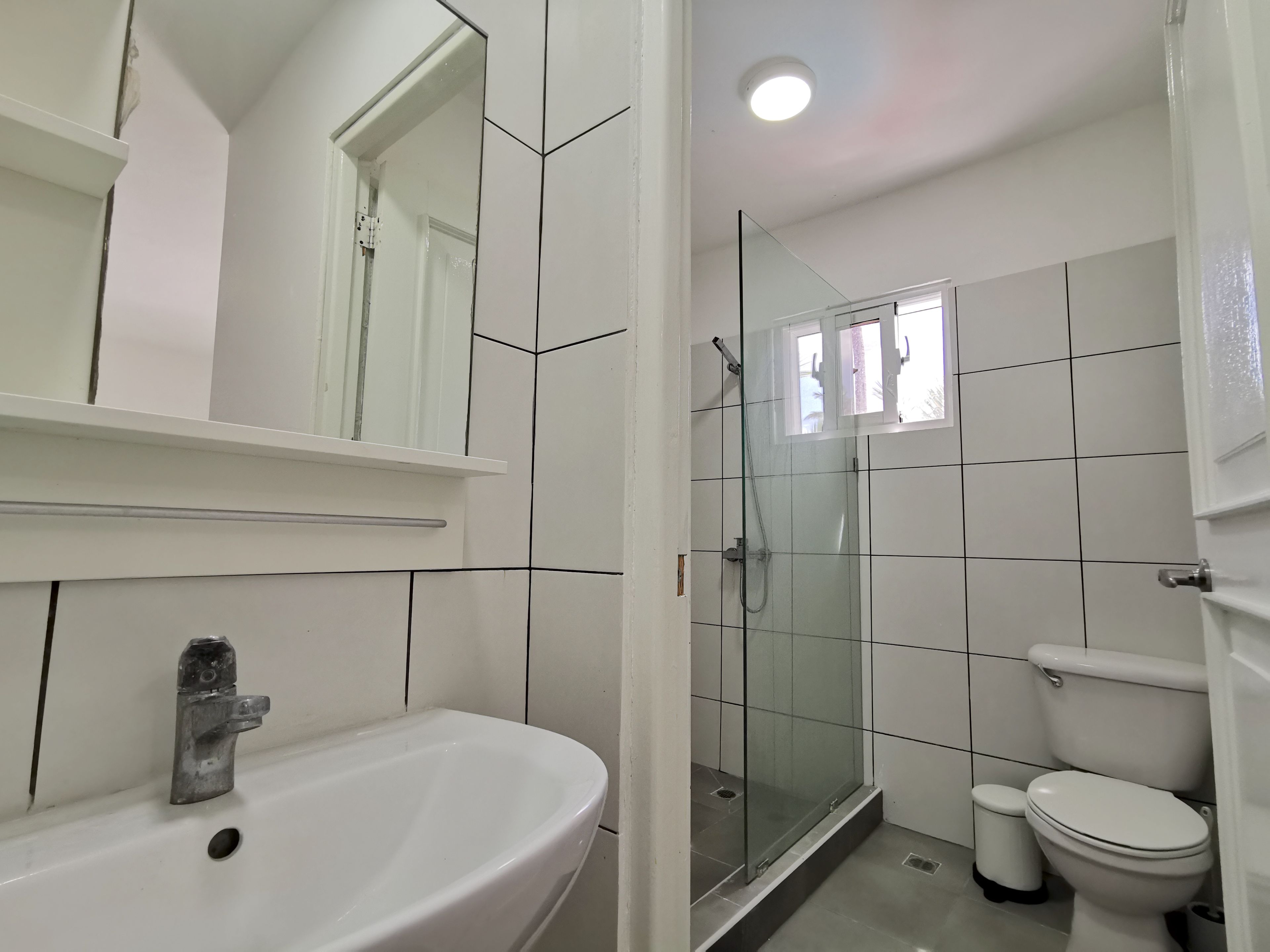 A bathroom with a white sink, a glass-enclosed shower, and a toilet.