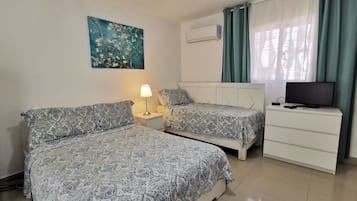 Ein Hotelzimmer mit zwei Betten, einem Fernseher, einem Schreibtisch und einem Bild an der Wand.
