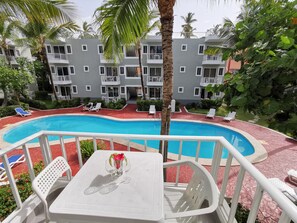 A pool area with lounge chairs and a table with a flower vase. - TROPICANA FAMILY CLUB playa LOS CORALES (La Altagracia Province)