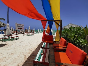 A beach with sun loungers, umbrellas, and a sign for a shopping center.