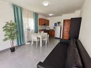 Un espacio habitable compacto con kitchenette, comedor y zona de estar.