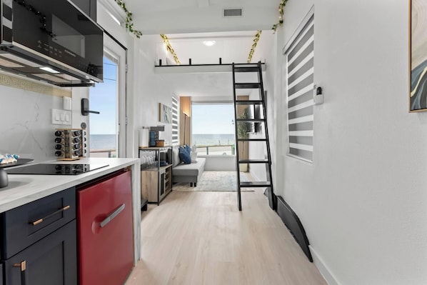 A modern kitchen with a built-in stove, red cabinets, and a view to the outside.