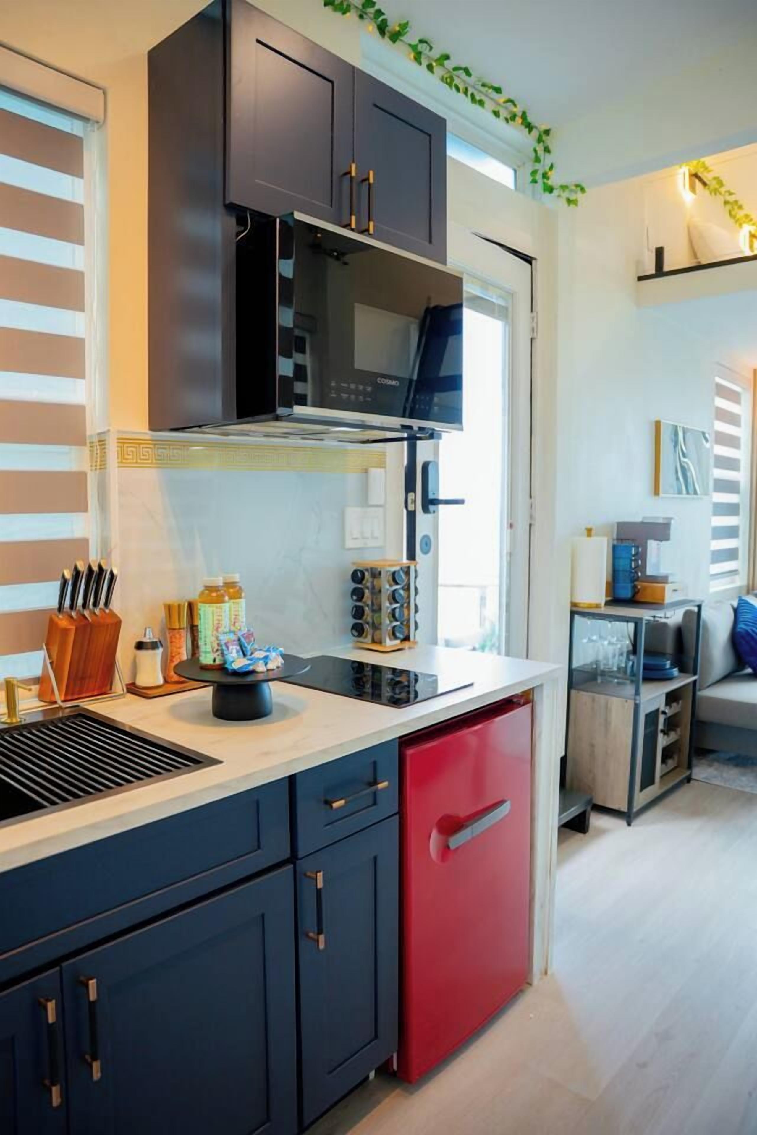 Una cucina moderna con mobili scuri, una lavastoviglie rossa e un forno a microonde integrato.
