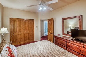 Ein Schlafzimmer mit Bett, Kommode, Spiegel und Kleiderschrank.